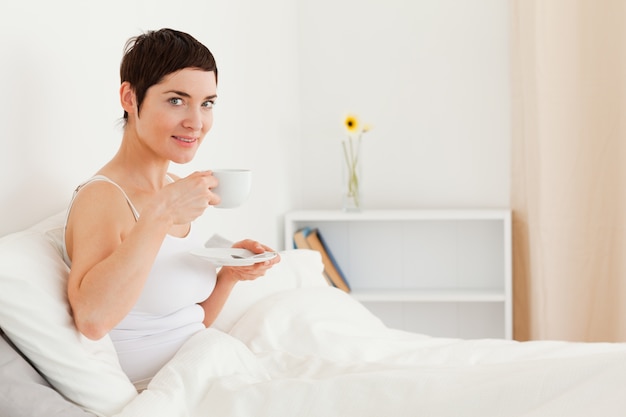 Leuke vrouw het drinken thee terwijl het bekijken de camera