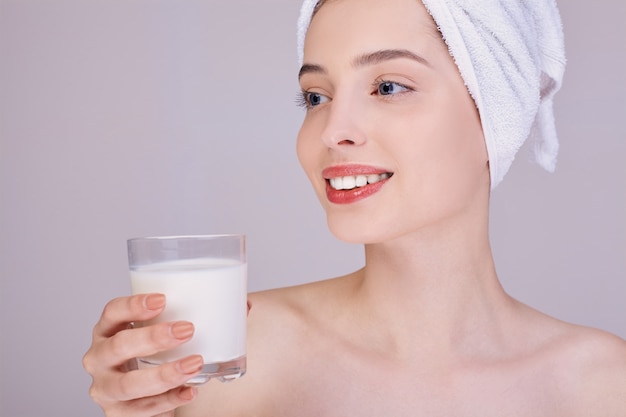 Leuke vrouw houdt een glas melk en glimlacht.