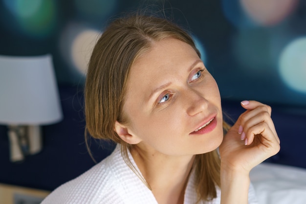 Leuke vrouw in een witte jas in bed gelukkige ochtend