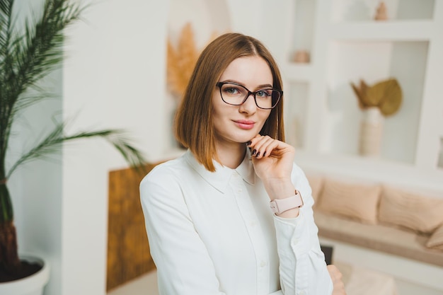 Leuke vrouw met een bril in een open ruimte coworking kantoor ontspannen ontspannen werken op afstand online dragen witte t-shirt en spijkerbroek