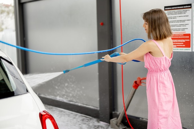 Leuke vrouw wast haar voertuig bij selfservice carwash