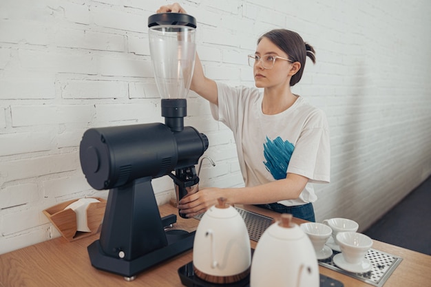 Leuke vrouwelijke barista die professionele koffiemachine gebruikt in cafetaria