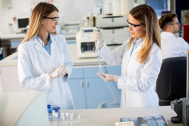 Leuke vrouwelijke onderzoekers in witte laboratoriumjas die in het laboratorium werken