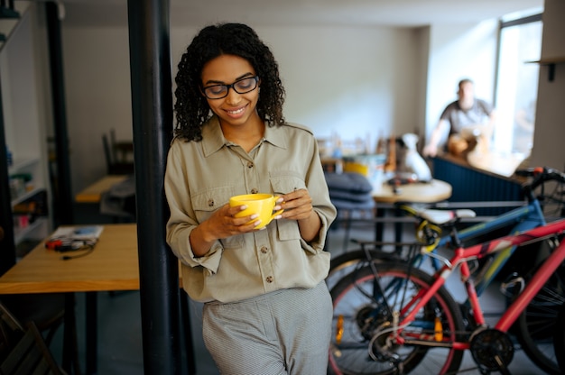 Leuke vrouwelijke student in glazen drinkt koffie in café. Vrouw die een onderwerp leert in koffiehuis, onderwijs en voedsel. Meisje studeert in campuscafetaria