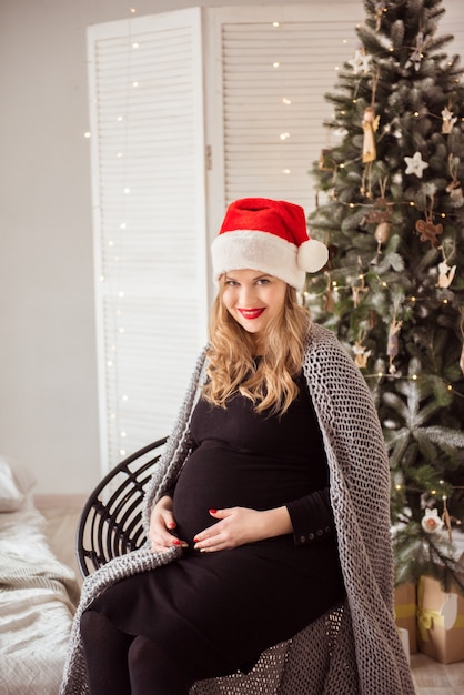 Leuke zwangere vrouw in Kerstmanhoed