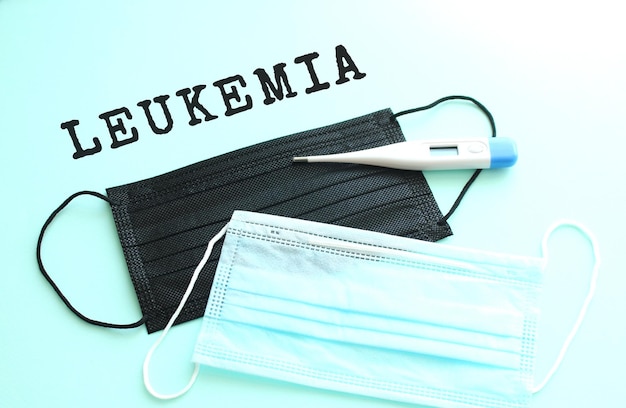 Leukemia lettering on a blue background with blue and black medical masks lying next to it