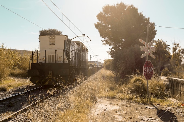 Железнодорожный переезд без шлагбаумов со знаком стоп при прохождении товарного поезда Сагунто Валенсия Испания