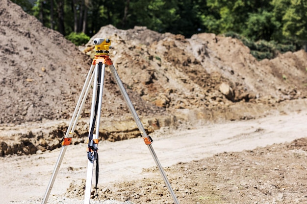 Foto livella su treppiede in lavori topografici. livello di misurazione in cantiere. geodesia del livello di controllo