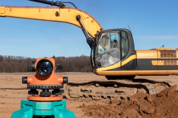 Photo level with an excavator in the background construction level or theodolite geodetic instruments and equipment for the construction and earthworks