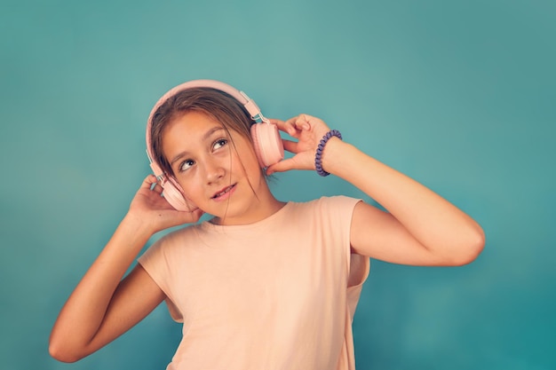 Levende en leuke emoties gelukkig kind met plezier luistert naar liedjes in draadloze koptelefoon gelukkig glimlachend kind meisje geniet luistert naar muziek in koptelefoon op blauwe achtergrond