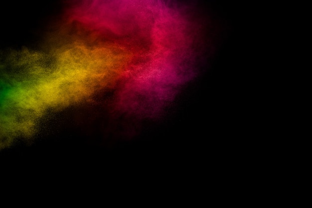 Levendige kleur stofdeeltjes exploderen op zwarte achtergrond.