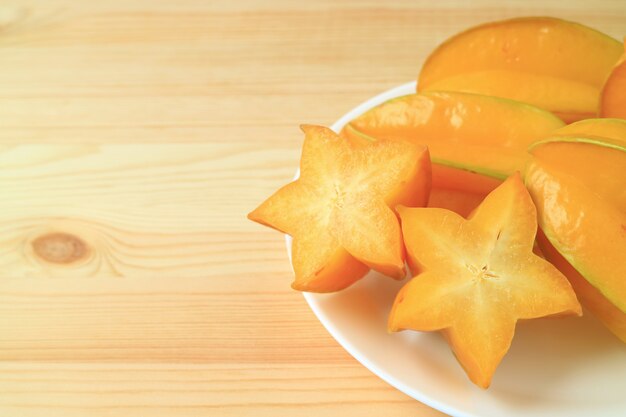 Levendige kleuren rijpe Star Fruit, gesneden en geheel op houten tafel, met vrije ruimte voor tekst en ontwerp