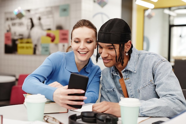 Levendige opname van twee jonge mensen die een selfie maken terwijl ze plezier hebben in de universiteitsbibliotheek