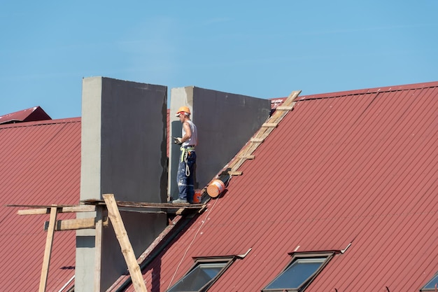 Levensbedreigende werkzaamheden op grote hoogte Een team dakdekkers werkt zonder verzekering op het dak Reparatie van het dak en ventilatieleidingen Overtreding van veiligheidsvoorschriften