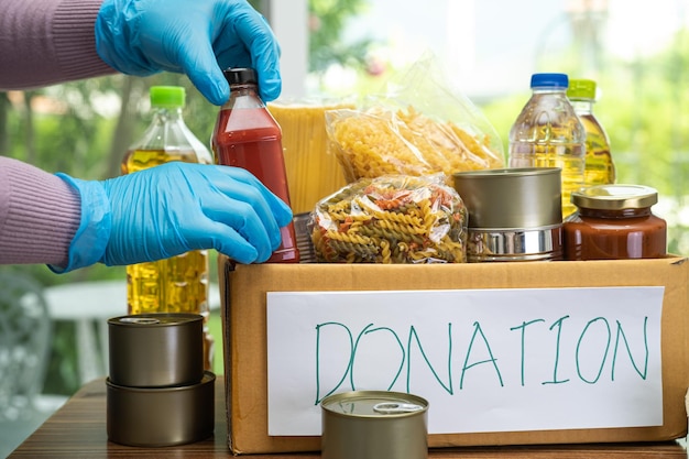 Foto levensmiddelen voor opslag en levering van donaties verschillende voedselpasta's, bakolie en ingeblikt voedsel in kartonnen doos