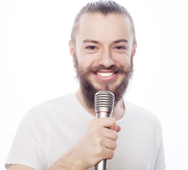 Levensstijl concept. een jonge man met een baard die een wit overhemd draagt met een microfoon en zingt
