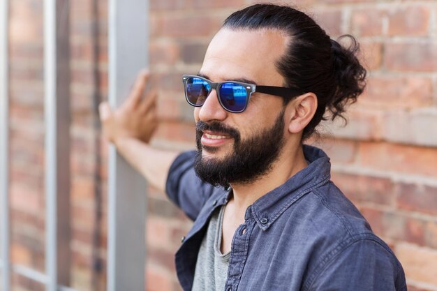 levensstijl, emotie, expressie en mensenconcept - gelukkig lachende man met baard en zonnebril op straat in de stad