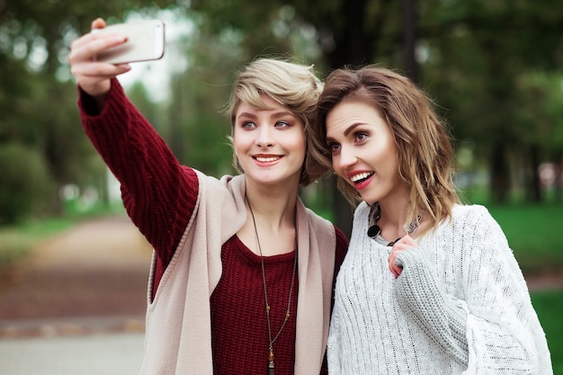 Levensstijl, geluk, emotioneel en mensenconcept: vrienden die selfie maken. Twee mooie jonge vrouwen die selfie maken in het herfstpark.