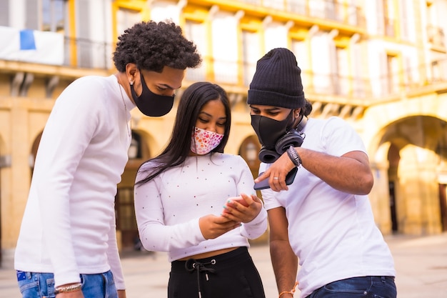 Levensstijl, Latino-vrienden die plezier hebben met gezichtsmaskers die naar iets aan de telefoon kijken.