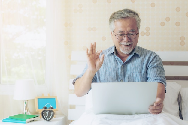 levensstijl Senior man met behulp van een laptop computer facetime-oproep aan familieleden