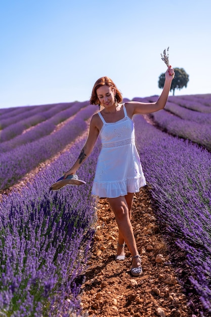 Levensstijl van een vrouw die lacht in een zomers lavendelveld in een witte jurk