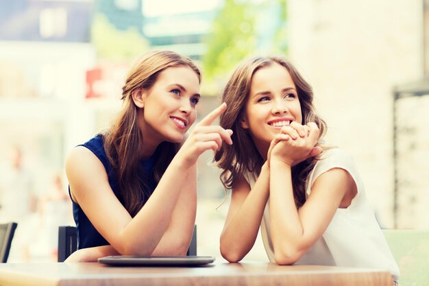 levensstijl, vriendschap en mensenconcept - gelukkige jonge vrouwen of tienermeisjes met tablet-pc in café buitenshuis