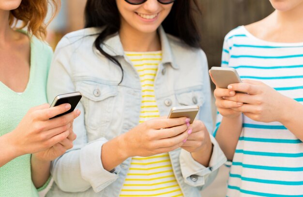 levensstijl, vrije tijd, technologie en mensenconcept - close-up van gelukkige jonge vrouwen met smartphone buitenshuis