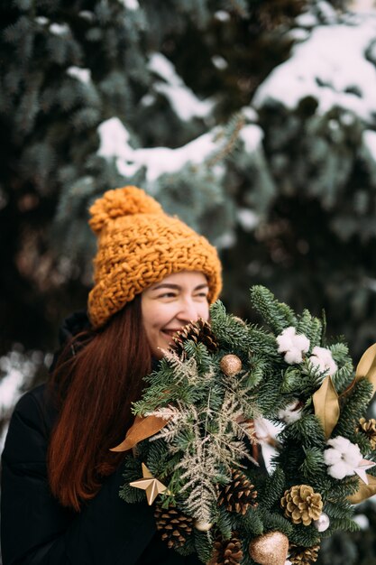 Levensstijlportret van glimlachend millennial meisje in oranje hoed. Besneeuwde kerstdag