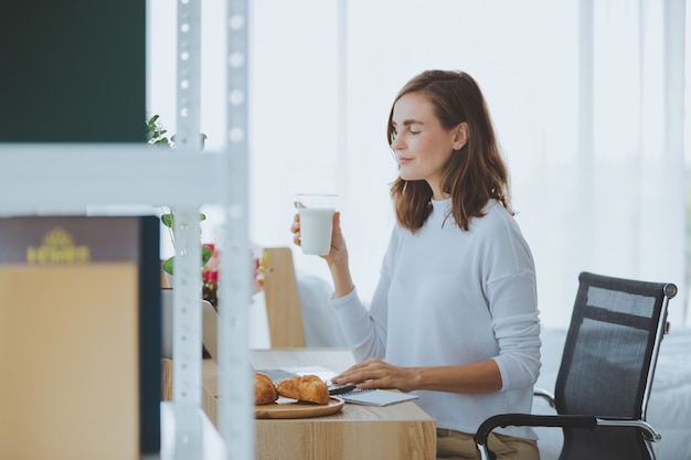 Levensstijlvrouw het werkende typen op laptop in modieuze ruimte thuis