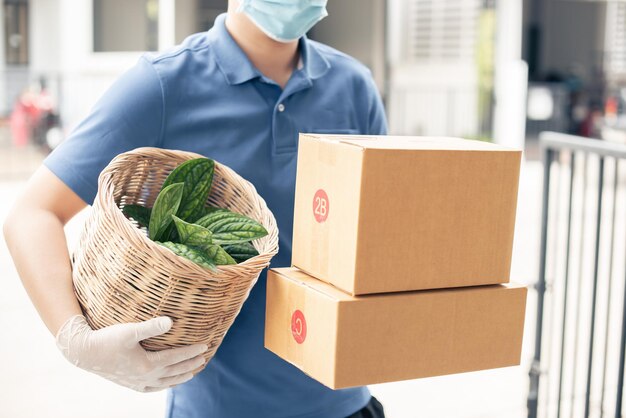 Levering Aziatische man draagt een beschermend masker in blauw uniform en is klaar om de voedselzak te bezorgen