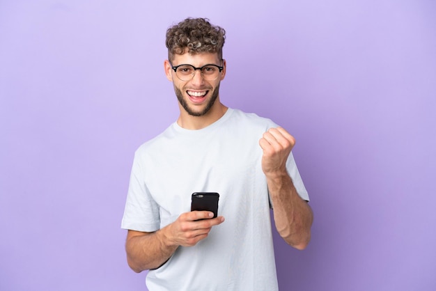 Levering blanke man geïsoleerd op paarse achtergrond met telefoon in overwinningspositie