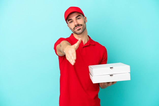 Levering blanke man oppakken van pizzadozen geïsoleerd op blauwe achtergrond handen schudden voor het sluiten van een goede deal