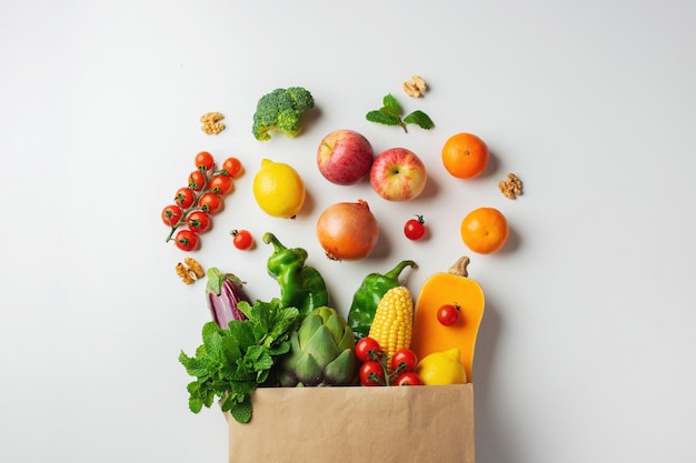 Levering gezonde voeding achtergrond. Gezond veganistisch vegetarisch eten in papieren zak groenten en fruit op wit. Winkelen voedsel supermarkt en schoon veganistisch eten concept.