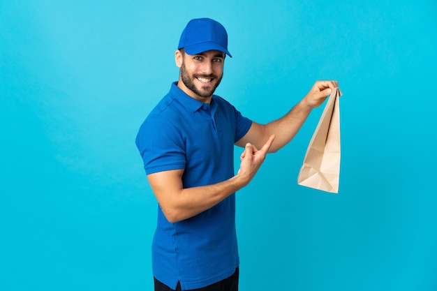 Levering man met baard geïsoleerd op blauwe muur en wijst erop