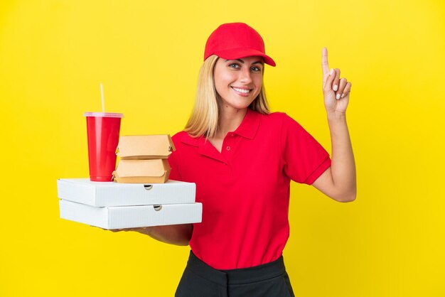 Levering Uruguayaanse vrouw met fastfood geïsoleerd op een gele achtergrond die een geweldig idee benadrukt