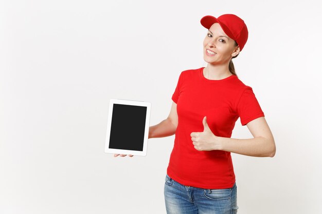 Levering vrouw in rode uniform geïsoleerd op een witte achtergrond. Glimlachende vrouw in pet, t-shirt, spijkerbroek die werkt als koerier of dealer, die tablet pc-computer met leeg leeg scherm naar camera laat zien. Ruimte kopiëren