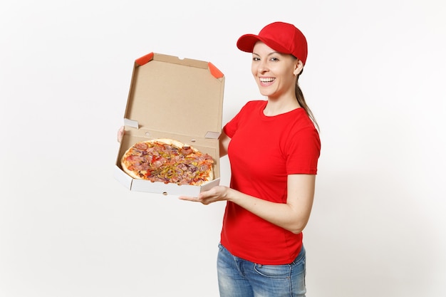 Levering vrouw in rode uniform geïsoleerd op een witte achtergrond. Mooie vrouw in pet, t-shirt, spijkerbroek die werkt als koerier of dealer met Italiaanse pizza in kartonnen flatbox. Kopieer ruimte voor advertentie.