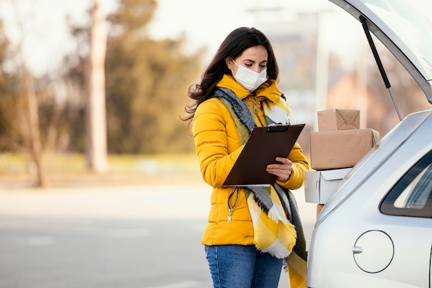 Foto levering vrouw met masker dragende pakket