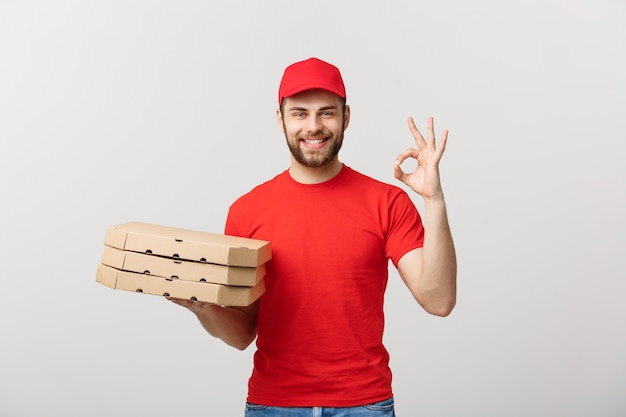 Leveringsconcept: Knappe pizzabezorger die OK teken maakt dat over grijs wordt geïsoleerd