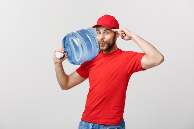 Leveringsconcept: Portret van de glimlachende koerier van de flessenwaterlevering in rood t-shirt