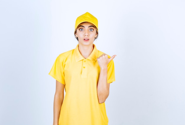 Leveringsvrouw in geel uniform staat en toont twee vingers in de buurt van de ogen.