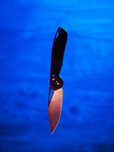 Photo levitating folding knife on neon trendy background