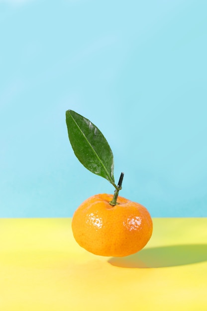 Levitation flying food tangerine with green leaf on yellow and blue