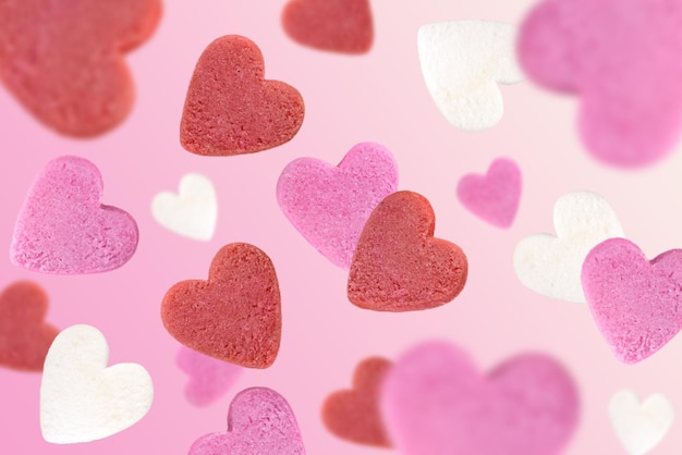 Foto levitazione di cuori di zucchero su sfondo rosa