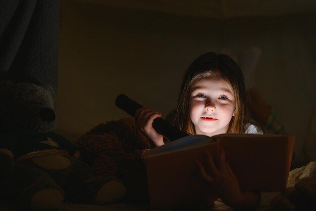 Lezen en familiespelletjes in kindertent Meisje met boeken en zaklamp voor het slapengaan