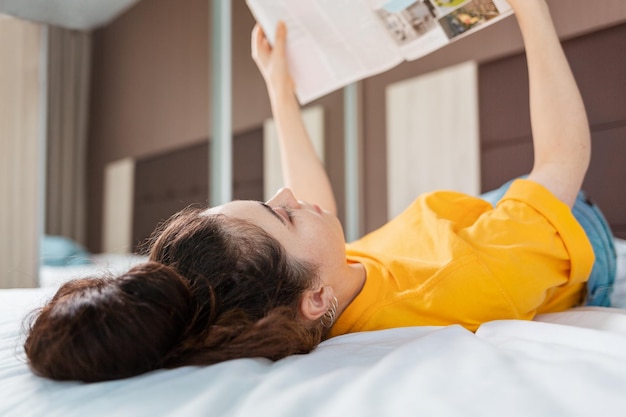 Lezen en onderwijs Een vrouw leest een tijdschrift liggend op het bed Indoor Close-up zicht van achter het hoofd