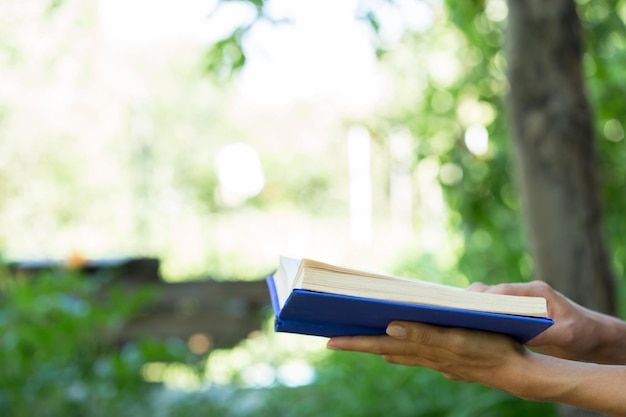 Lezen en onderwijs in het zomerconcept meisje met een open boek dat buiten in een tuin leest