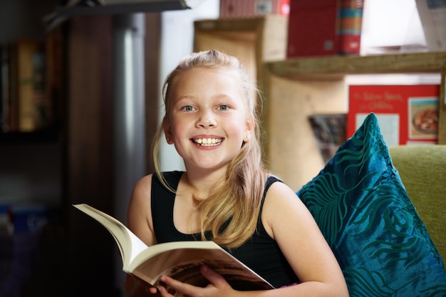 Lezen en ontspannen is de beste combinatie Portret van een schattig blond meisje ontspannen en lezend op de bank