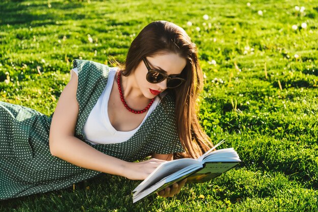 Lezende vrouw op gras Voorbereiding van student in park, zonnebril