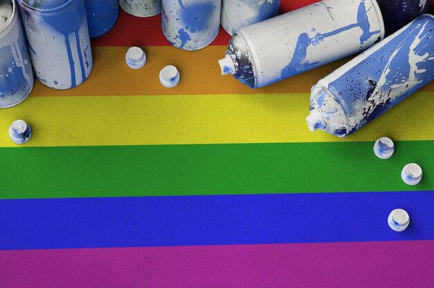 Lgbt community flag and few used aerosol spray cans for\
graffiti painting street art culture concept